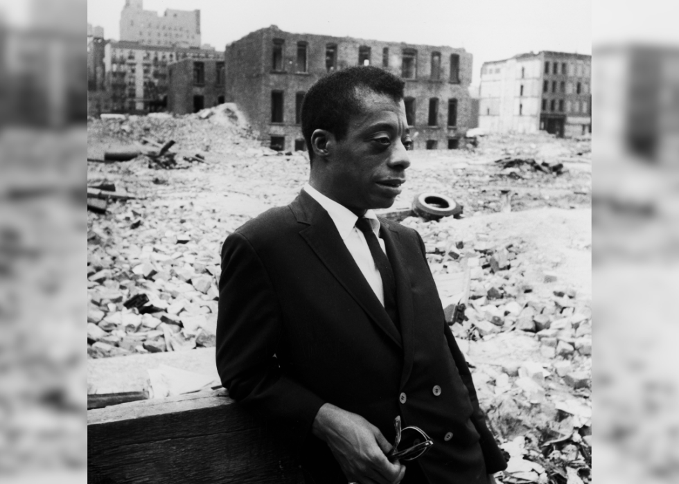 James Baldwin stand in mijlocul cladirilor demolate si al molozului.