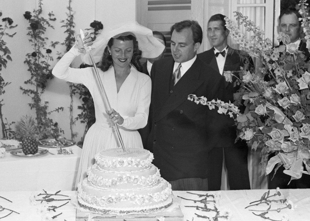 Rita Hayworth, impreuna cu sotul ei, Printul Aly Khan, le taie tortul de nunta cu o sabie.
