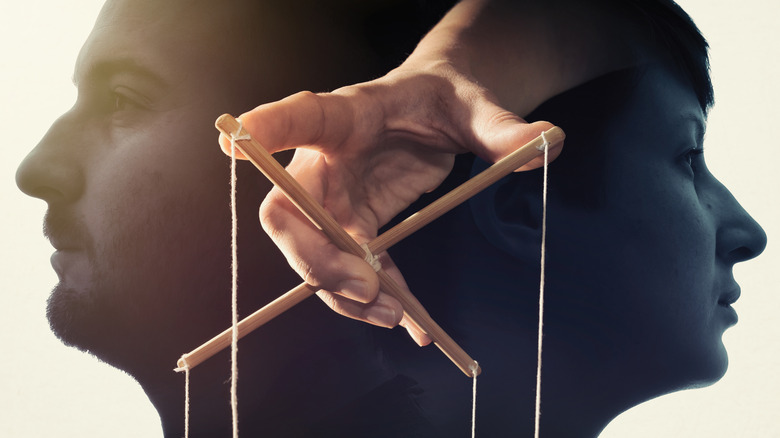 Barbat si femeie de profil cu mana suprapusa care controleaza sirurile de papusi