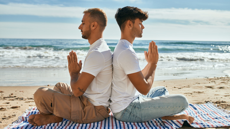 cuplu care face yoga si meditatie pe plaja